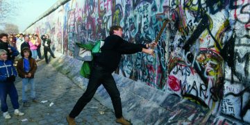 A man welds a pickaxe to participate in the destruction of the Berlin Wall, between the Postdam Platz and the Brandenburg Gate. The Berlin Wall separated East and West Berlin for over 28 years. (Photo by Jacques Langevin/Sygma/Sygma via Getty Images)